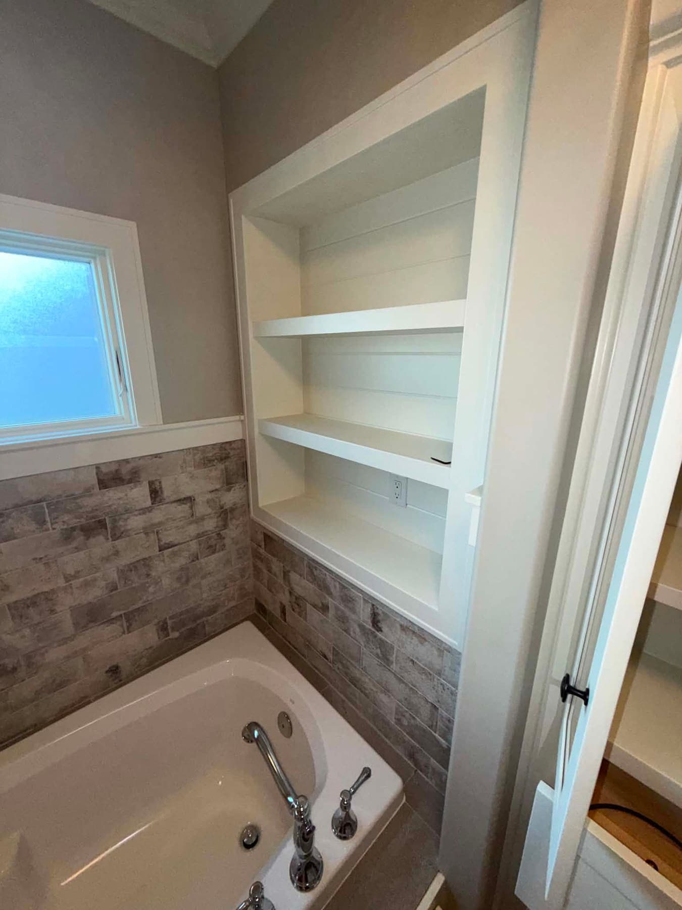 Bathtub with built-in shelves and a stone-look wall, cleaned