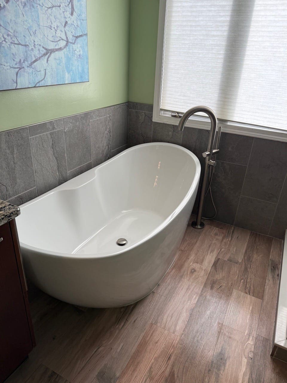 Freestanding white soaking tub next to a wood-look floor, cleaned