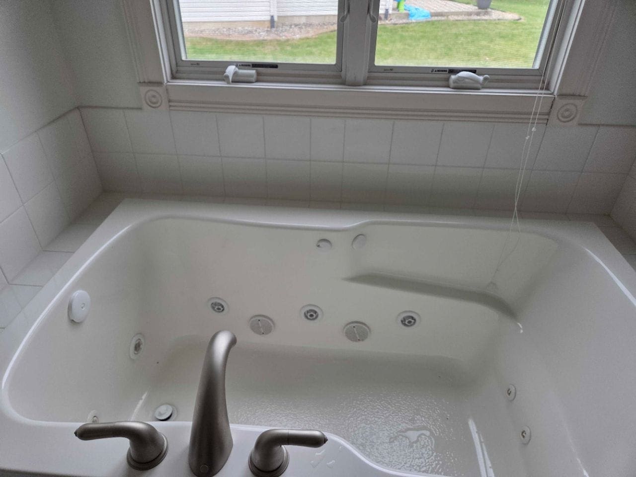Jetted corner tub under a window, cleaned and free of water spots