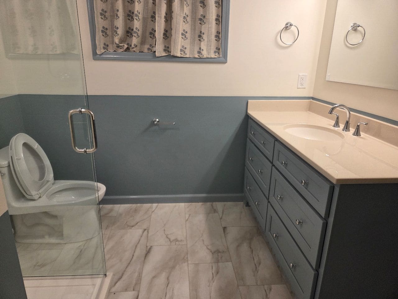 Bathroom with a vanity, a glass shower door, and gray-blue wall paint, cleaned
