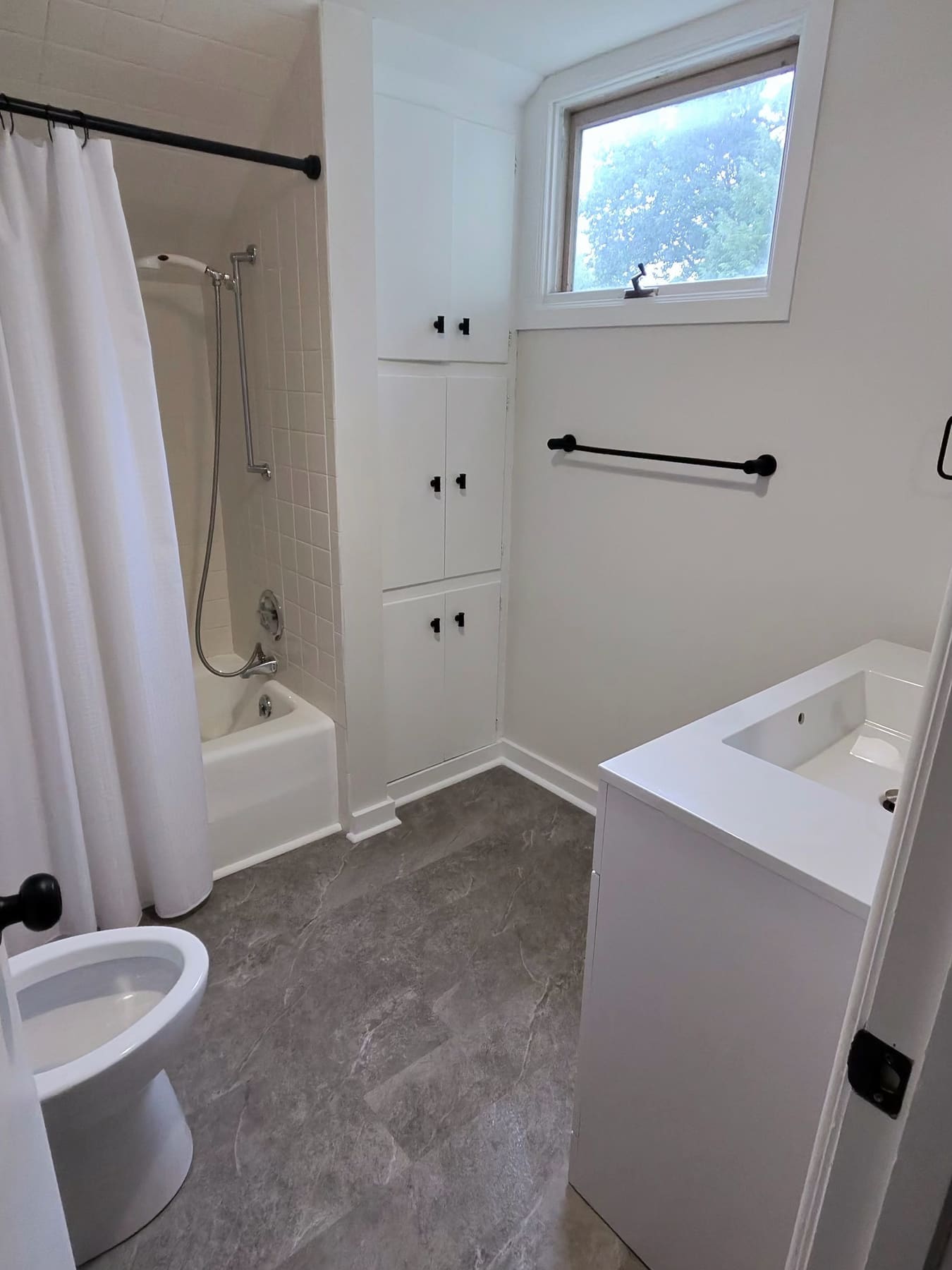 Bathroom with a tub, a window, and a white vanity, cleaned