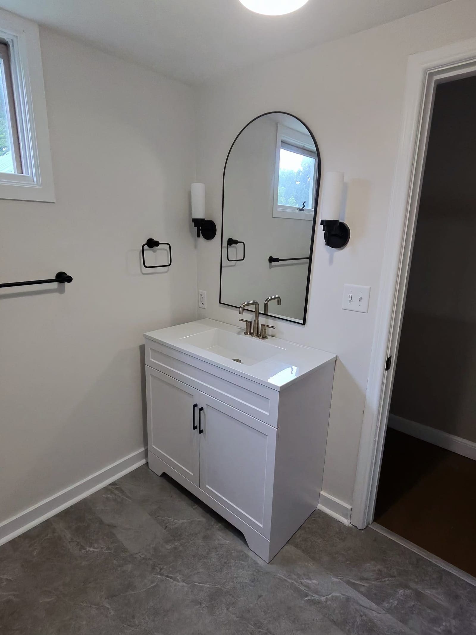 White bathroom vanity with a mirror and black fixtures, cleaned
