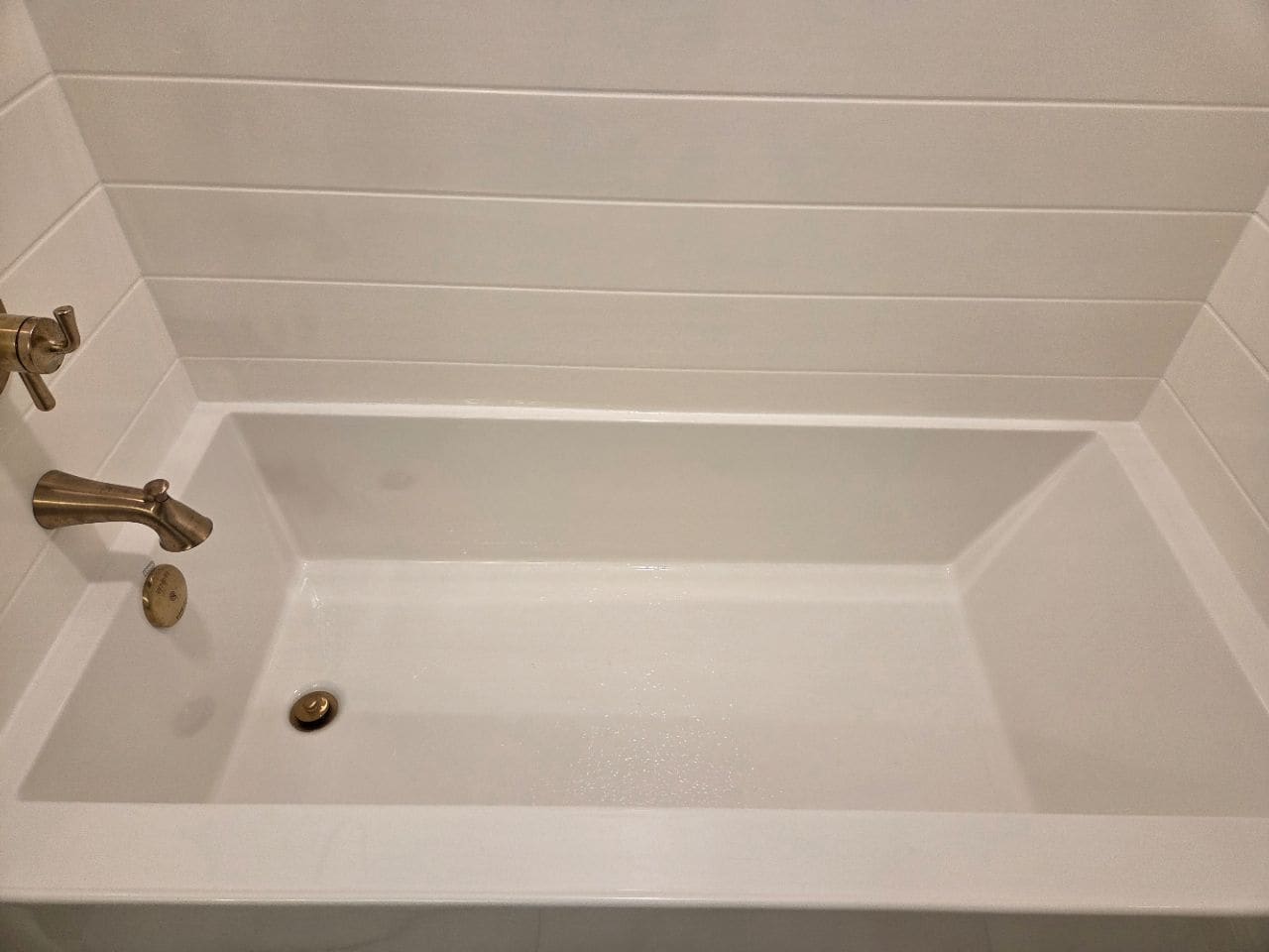 Soaking tub with brass fixtures and a shiplap surround, cleaned