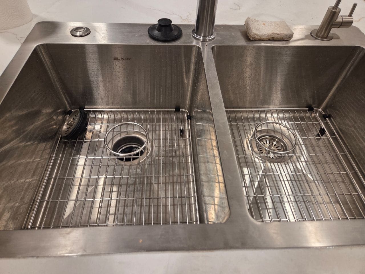 Double stainless kitchen sink with sink grids and a faucet, cleaned