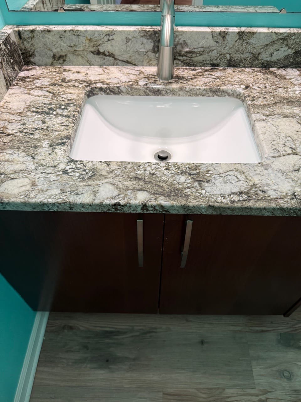 Close-up of a white undermount sink on a granite counter with a chrome faucet, cleaned