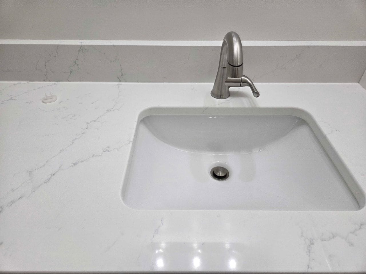 White undermount sink with a chrome faucet on a quartz counter, free of spots