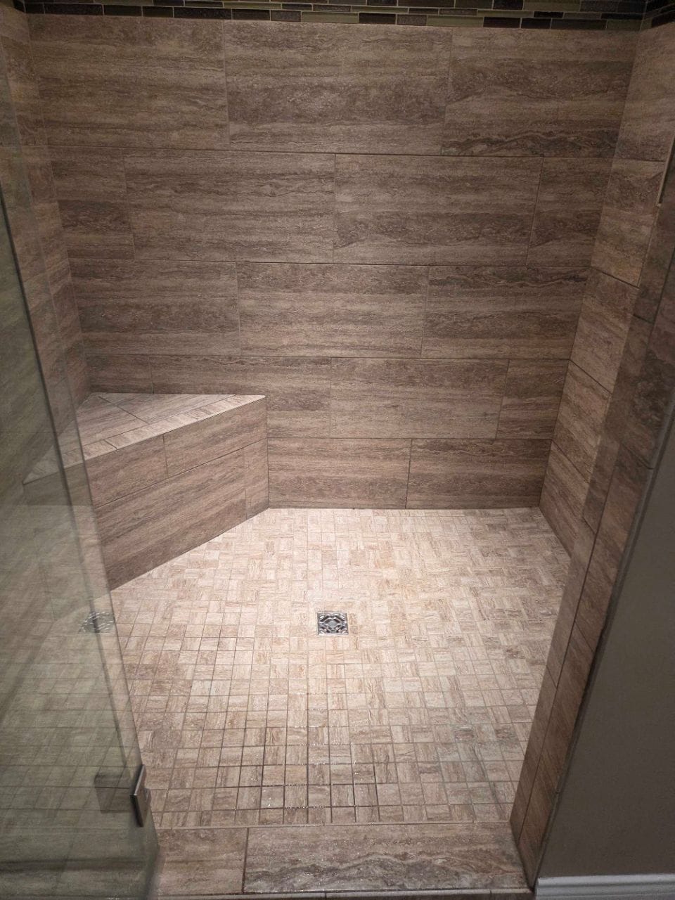 Tiled walk-in shower with a built-in bench and a mosaic floor, cleaned