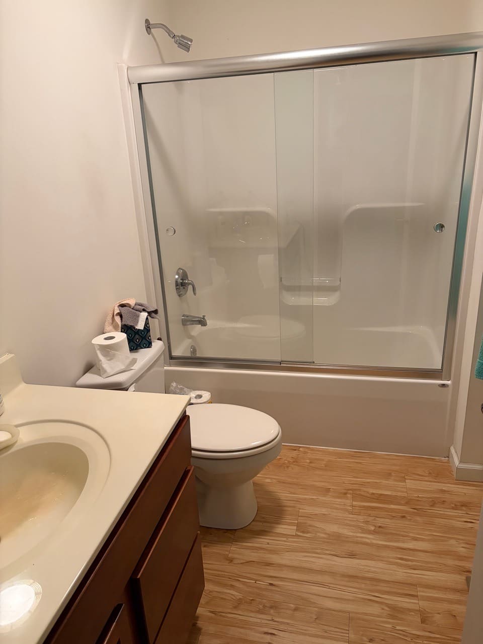 Tub-shower with a sliding glass door on a wood-look floor, cleaned