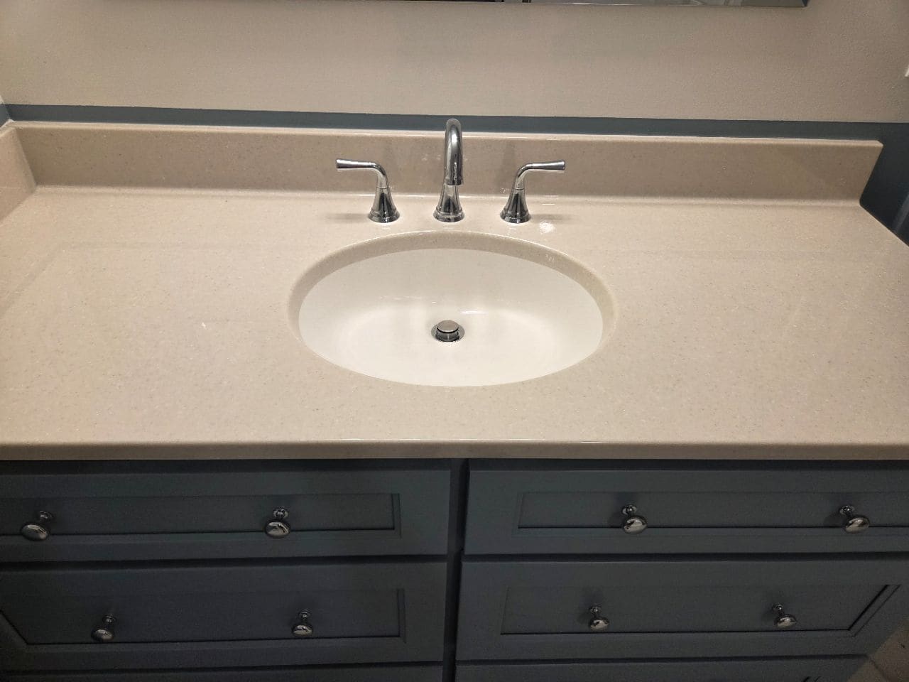 Cream counter with a white sink and chrome faucet over dark cabinets, cleaned