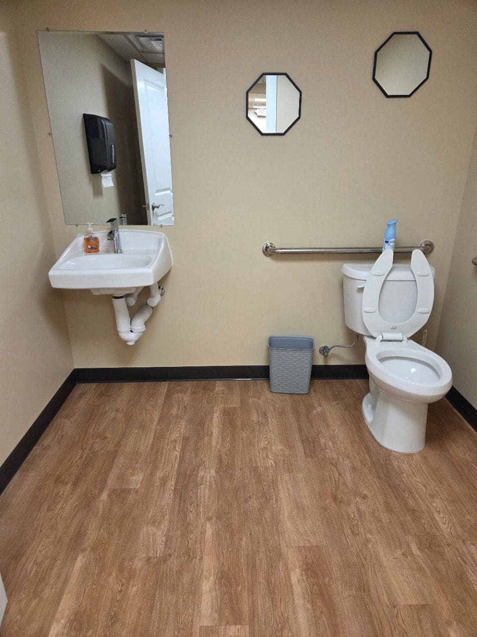 Restroom with a wall-mounted sink, a grab bar, and a toilet, cleaned