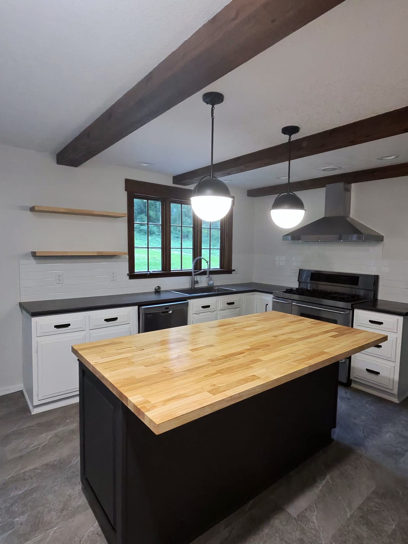 Kitchen with a butcher-block island, black island base, pendant lights, and exposed ceiling beams, cleaned