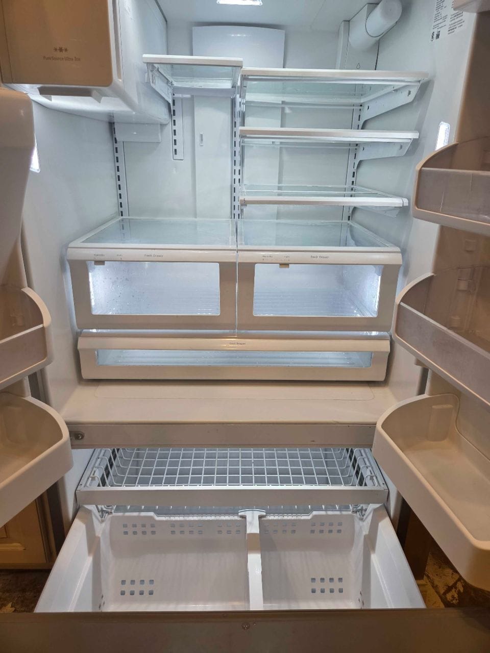 Open refrigerator with empty, clean shelves and drawers
