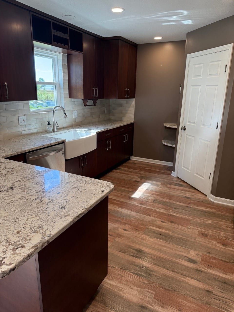 Kitchen with a granite counter, farmhouse sink, and wood-look floor, cleaned