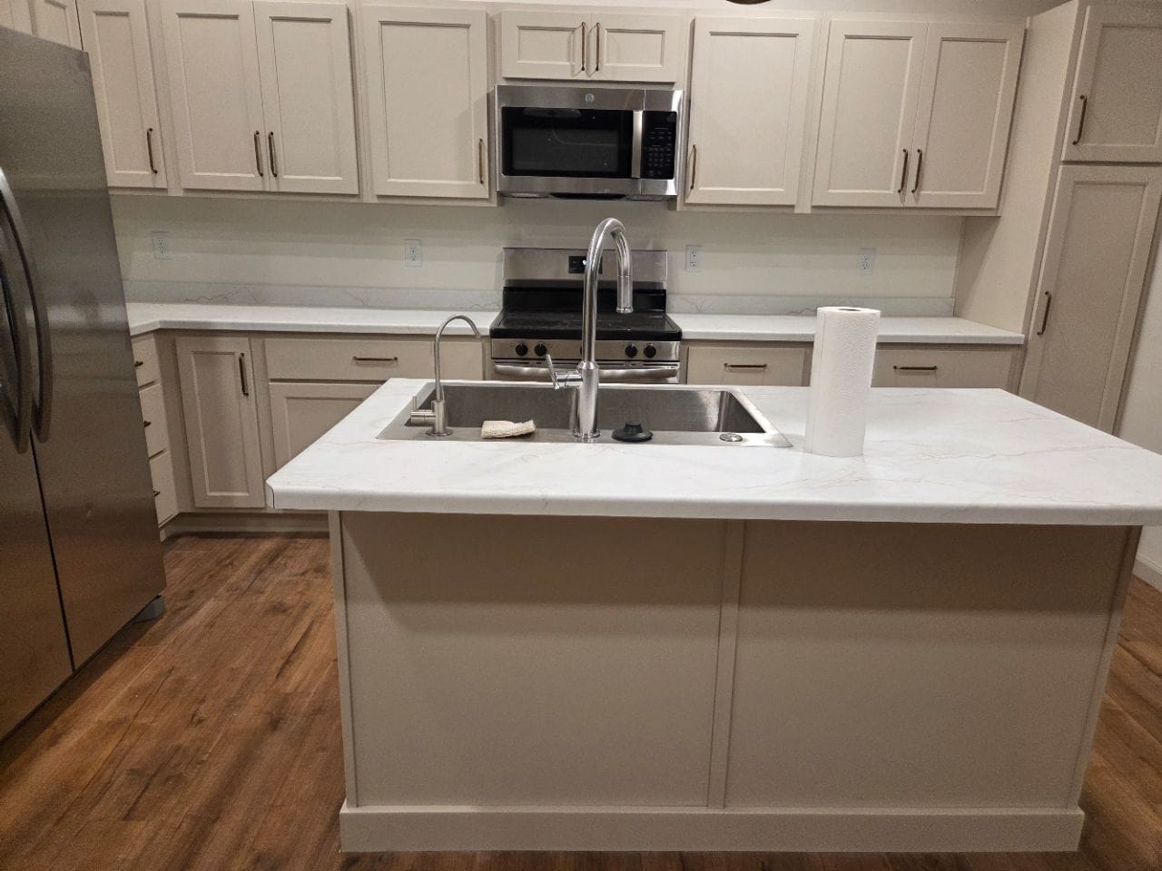 Kitchen with a white island and sink, white cabinets, and stainless appliances, cleaned