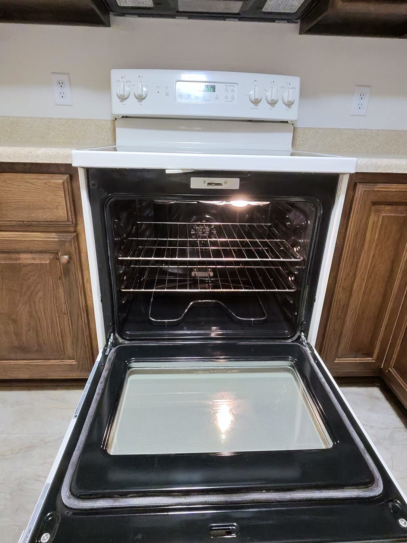 Open oven with a clean interior and racks, on a kitchen floor