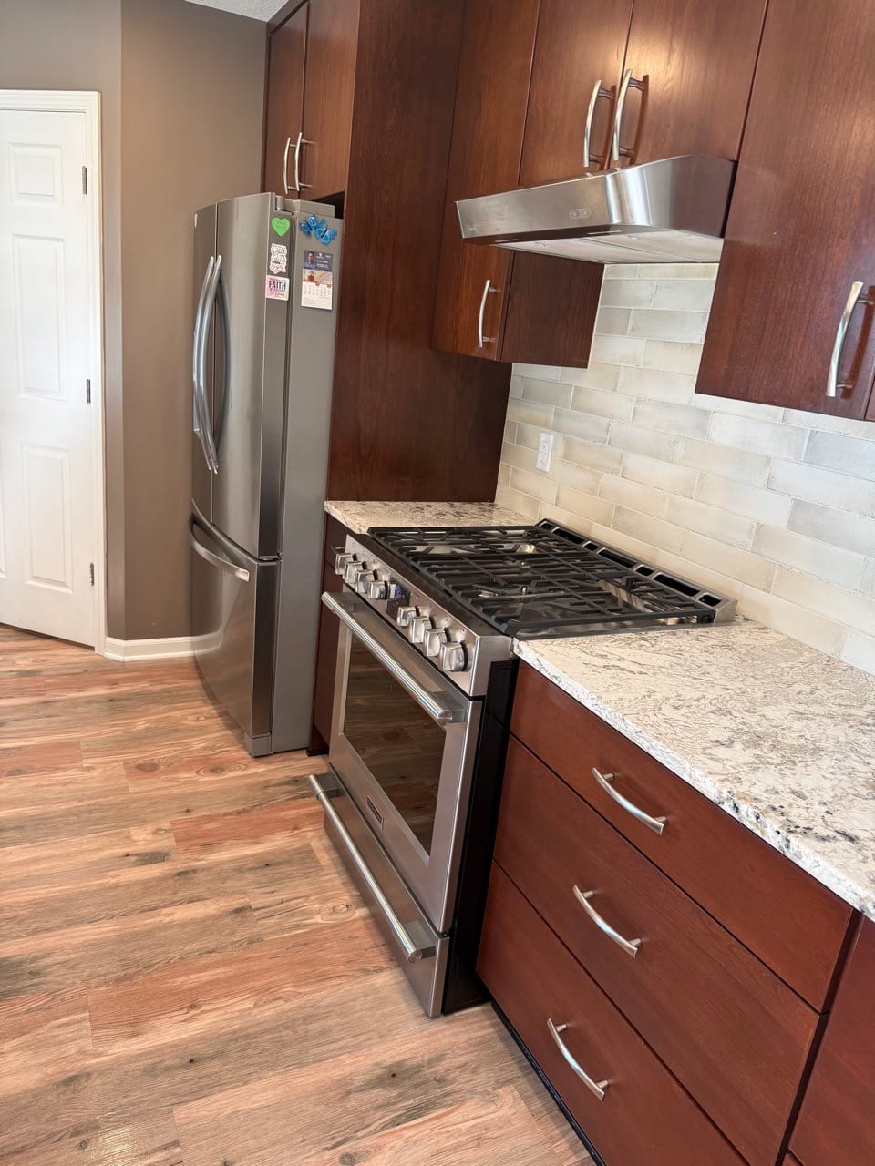 Kitchen with a stainless range, refrigerator, and wood-look floor, cleaned