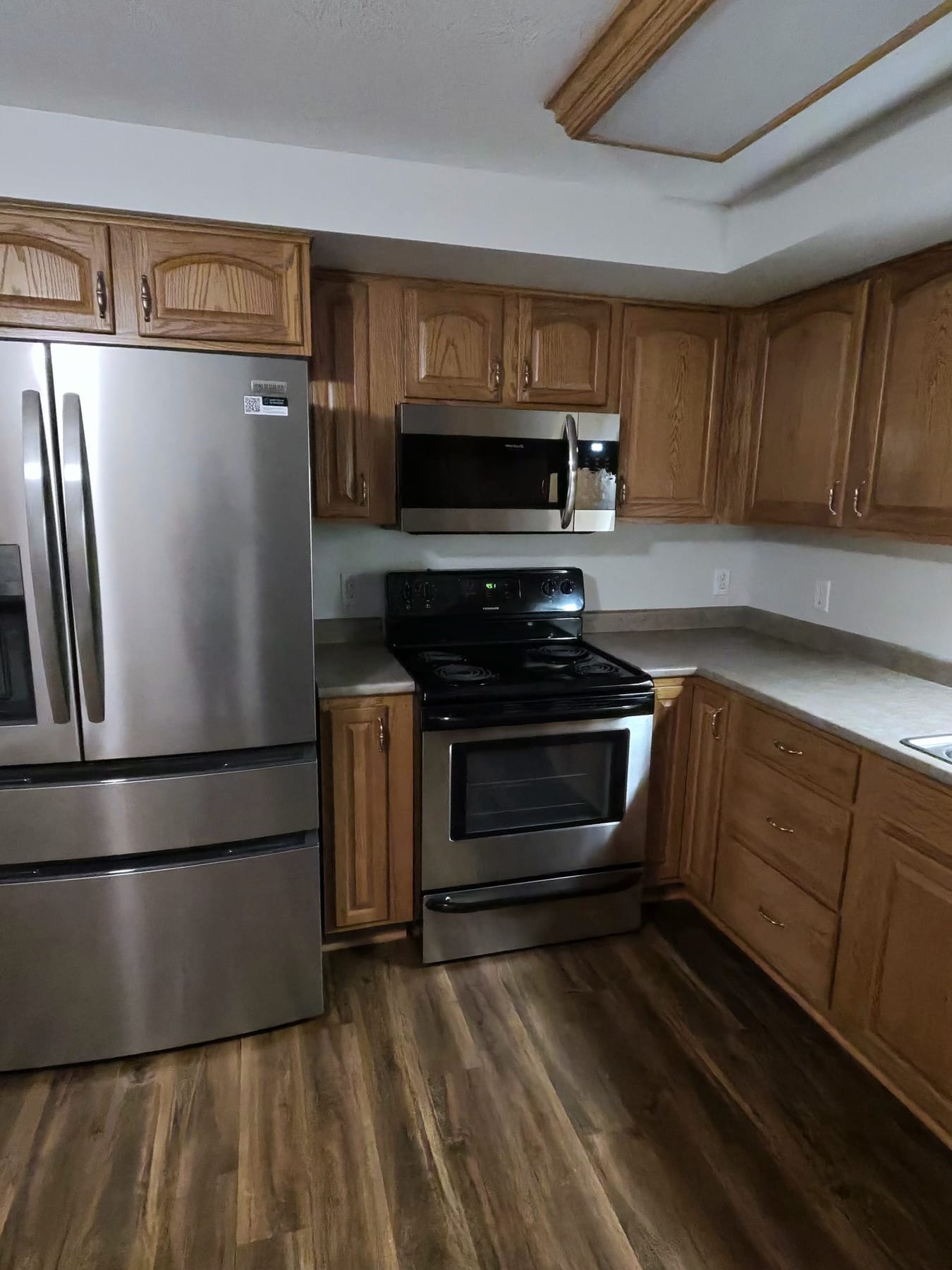 Kitchen with a stainless steel refrigerator, range, and microwave, wiped clean