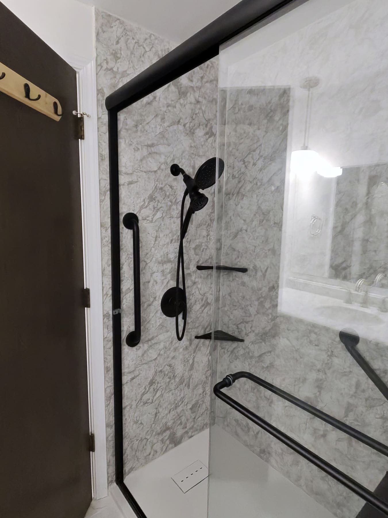 Walk-in shower with marble-look walls and black fixtures, cleaned